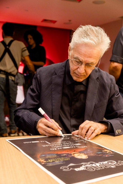 Caetano Veloso autografando um cartaz do Prêmio UBC